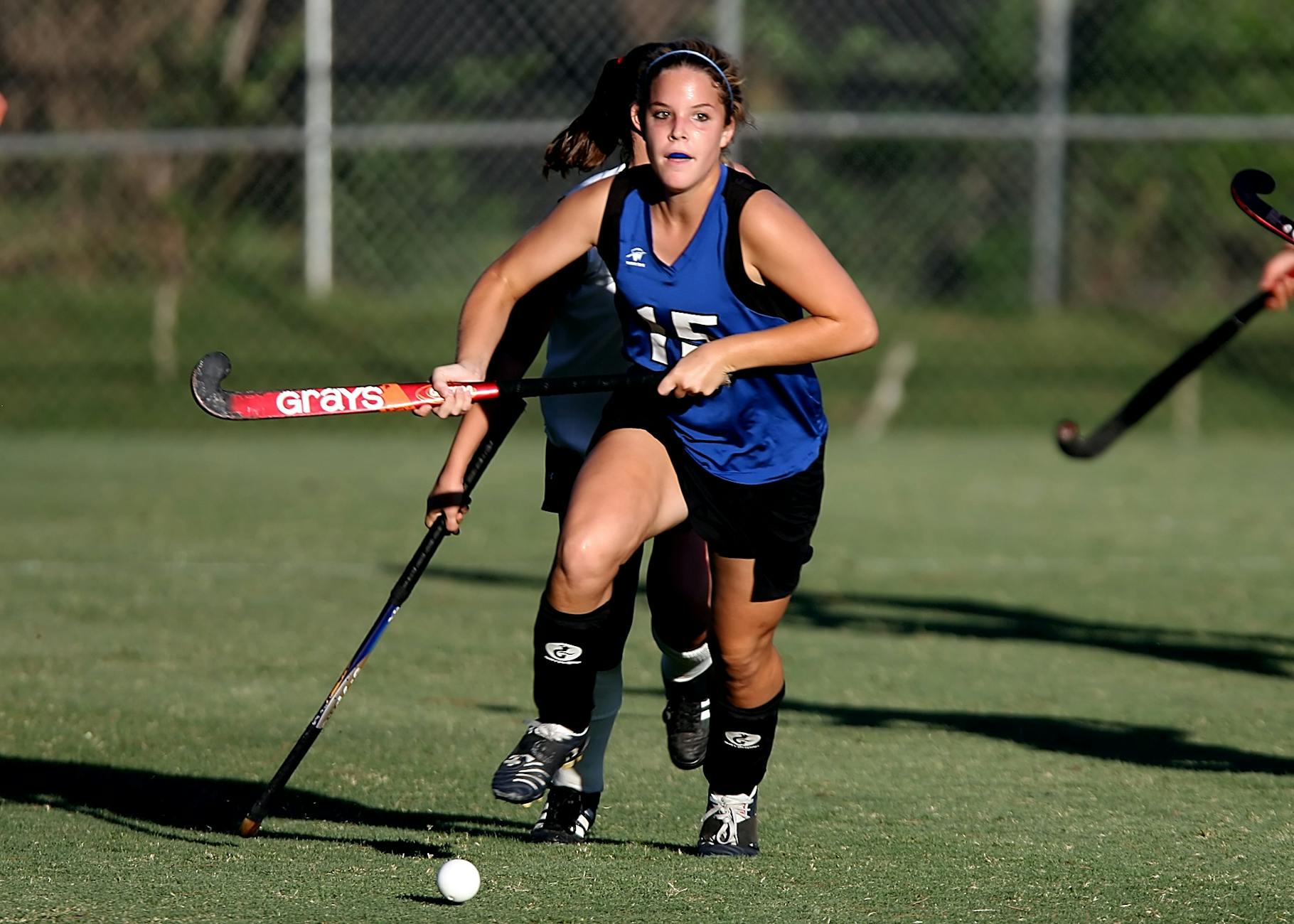 woman wearing blue and black jersey holding field hockey