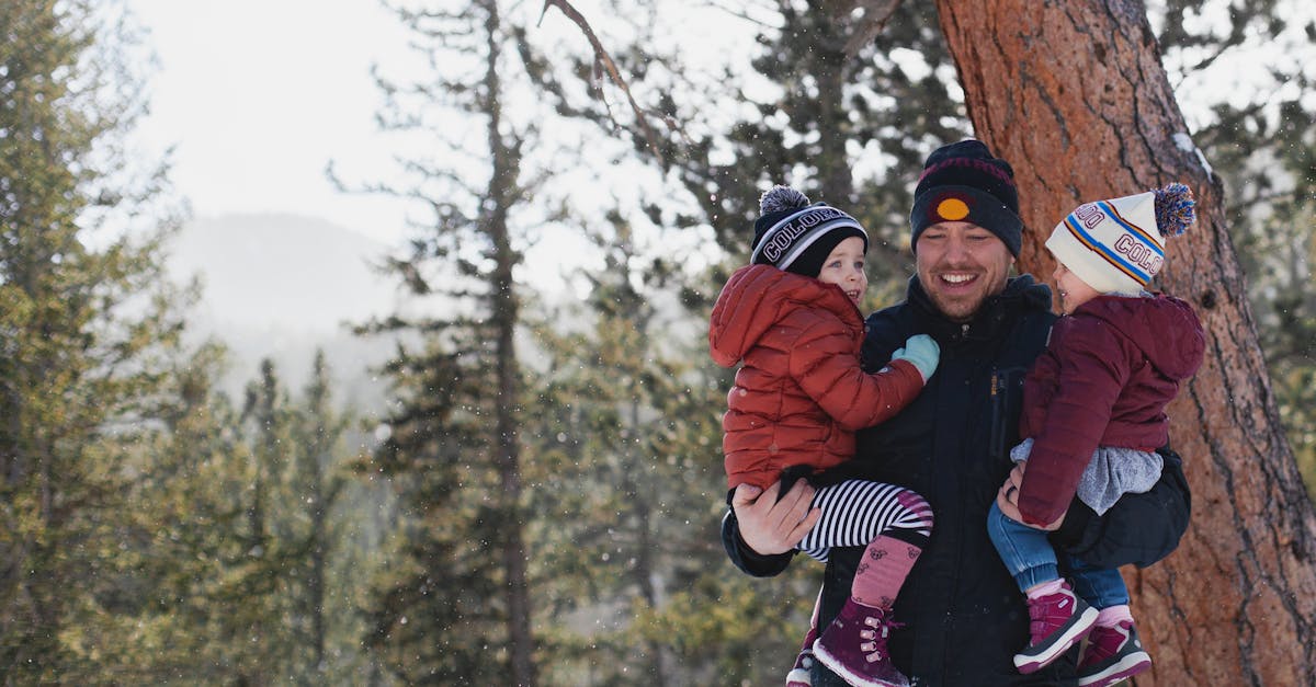 A joyful father holding his children in a snowy forest during winter, creating lasting memories.