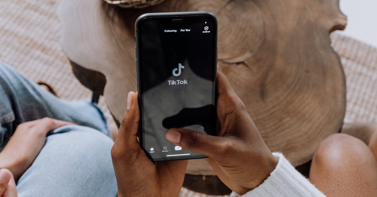 Close-up of hands holding a smartphone displaying the TikTok app interface on a wooden surface.