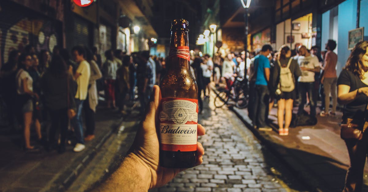 Enjoy the vibrant city nightlife with a Budweiser in hand amidst a bustling street crowd.