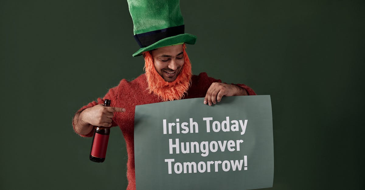 Happy man dressed as a leprechaun holding a themed sign and drink.