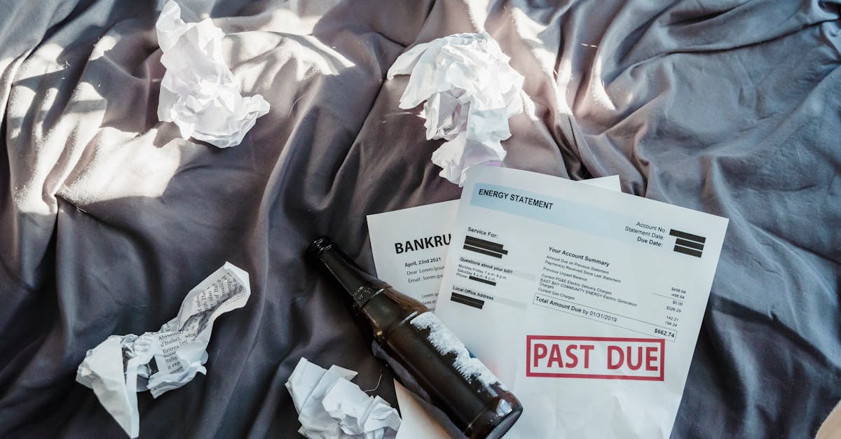 Scene of financial distress with bankruptcy notice, past due bills, and crumpled papers on a bed.